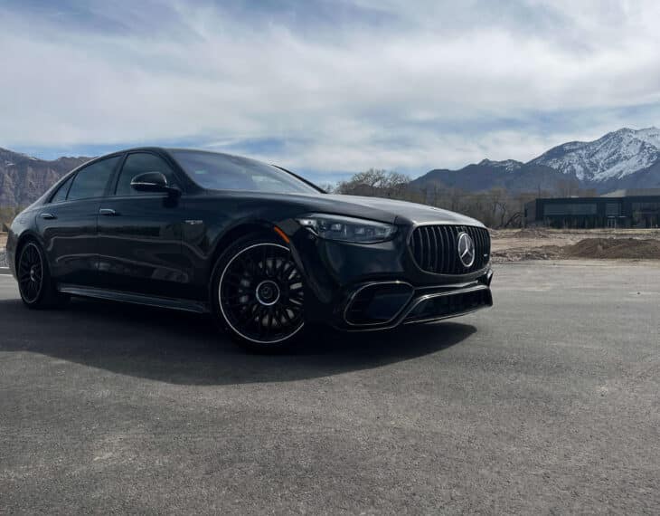 IAC armored Mercedes-AMG S63 4-door luxury sports car in black, parked outdoors with mountains on the side